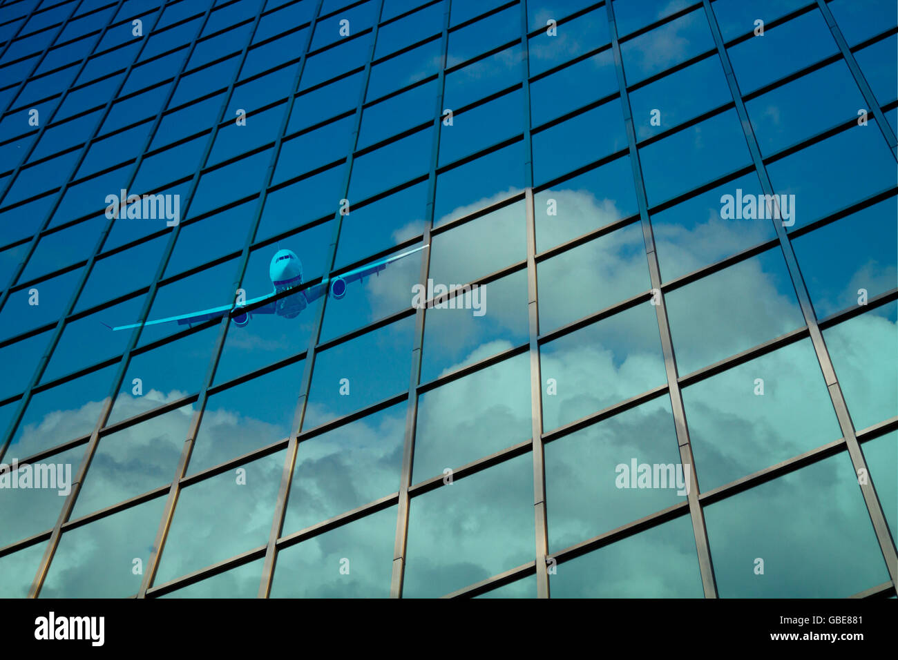 Aeroplano riflettere su un vetro cortina muraria con blu cielo nuvoloso Foto Stock