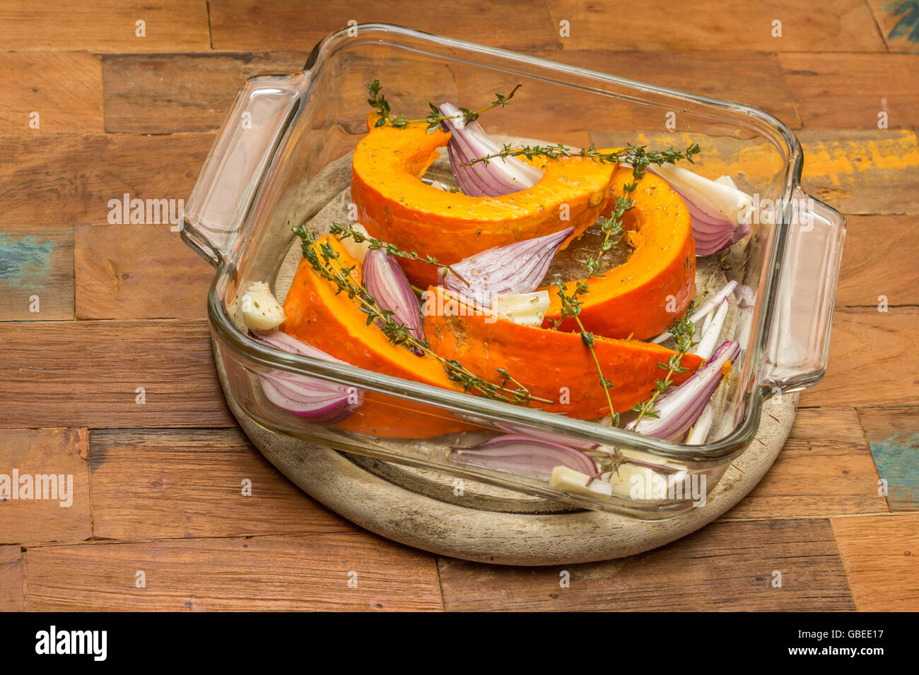Fette di zucca con cipolla rossa, aglio e timo in una teglia Foto Stock