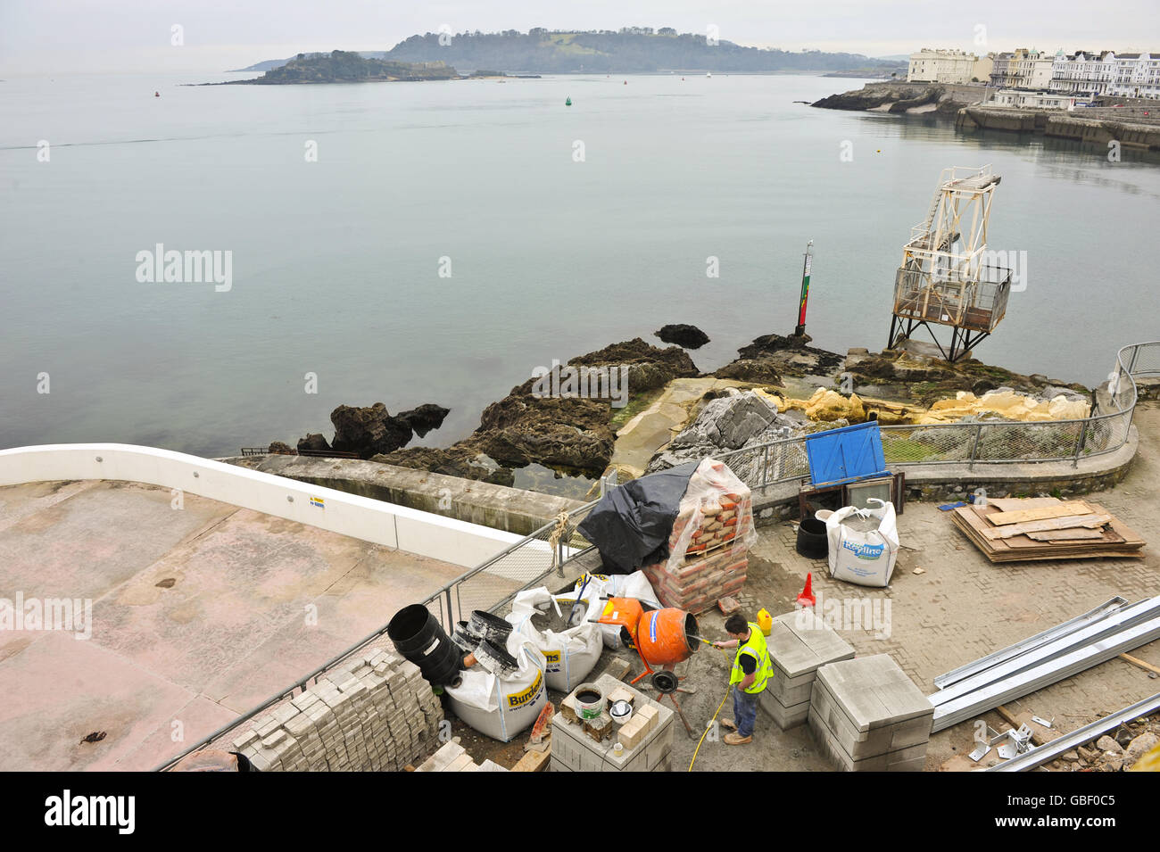 Un lavoratore mescola cemento nel sito di ristrutturazione di TInside Lido, Plymouth Hoe Foto Stock