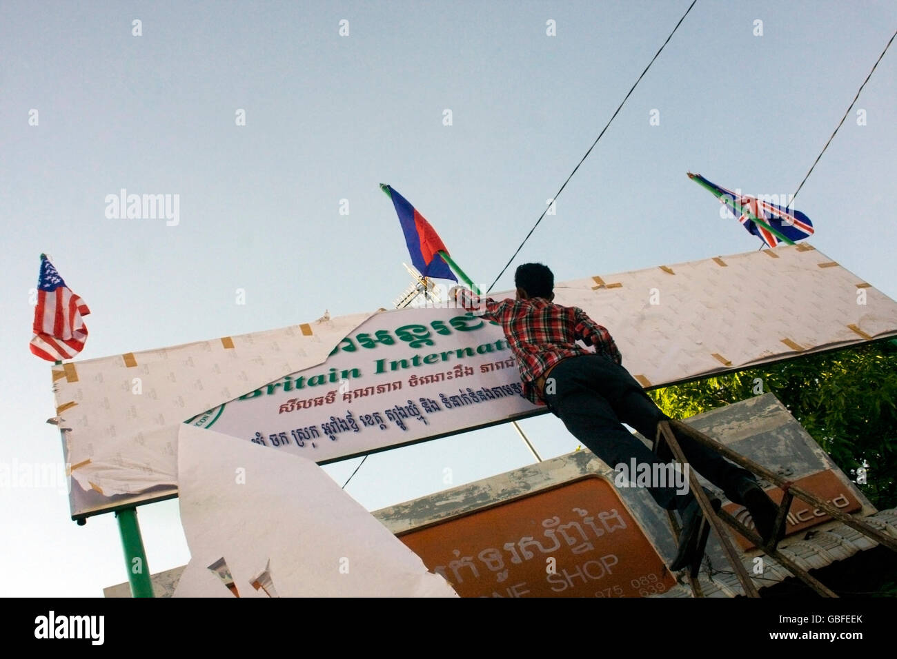 Un uomo è la scopertura di un segno che indica la posizione di una nuova scuola di lingua inglese nel villaggio di Chork, Cambogia. Foto Stock
