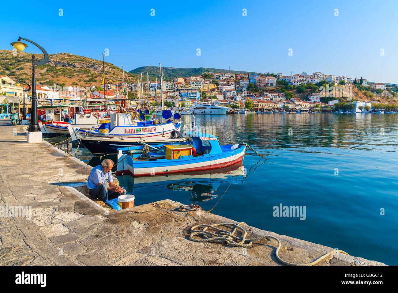 PYTHAGORION PORTA, isola di Samos - Sep 19, 2015: pescatore è preparare il pesce appena pescato nel bellissimo porto di Pythagorion a Samos Foto Stock