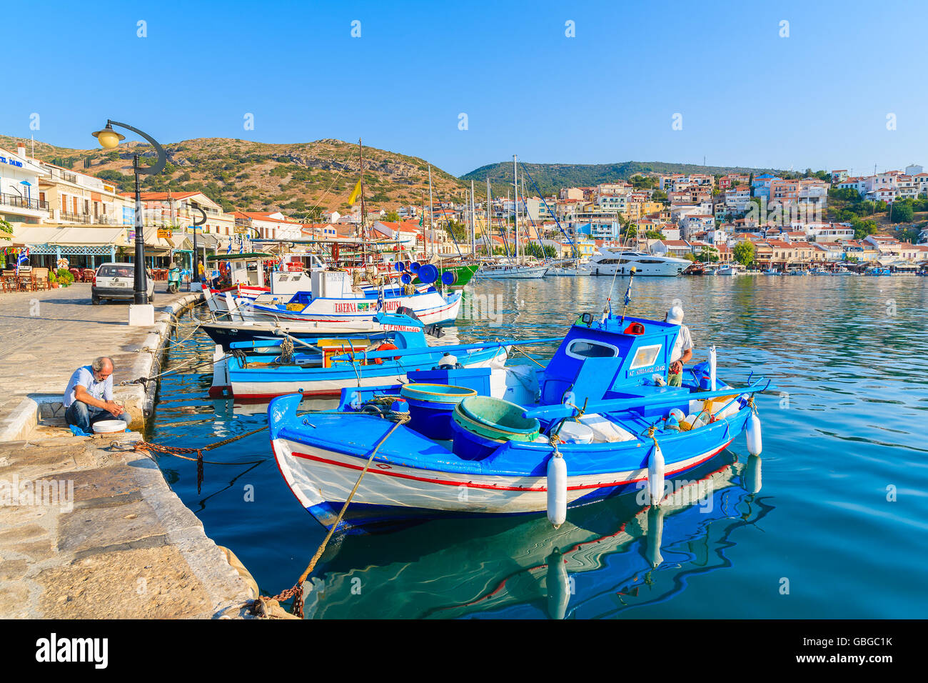 Isola di Samos, Grecia - Sep 19, 2015: pescatore lavora vicino tradizionale blu e il colore bianco greco barca da pesca in Pythagorion Foto Stock