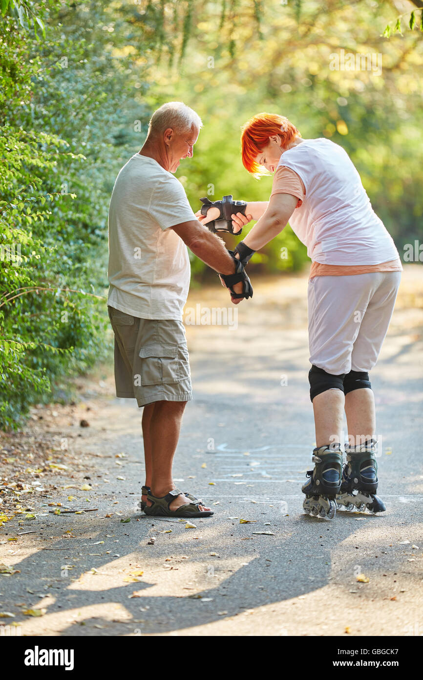 Senior donna imparare a pattinare con suo marito nel parco Foto Stock