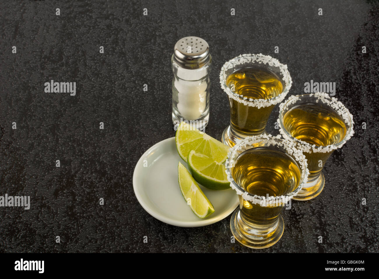 Tequila scatti con calce su sfondo nero. Bere alcool. Oro tequila messicana. Tequila shot. Tequila. Foto Stock