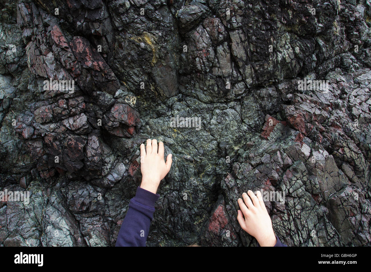 Mani aggrappati dalla punta delle dita e salendo su un aspro, roccia di granito faccia. Foto Stock