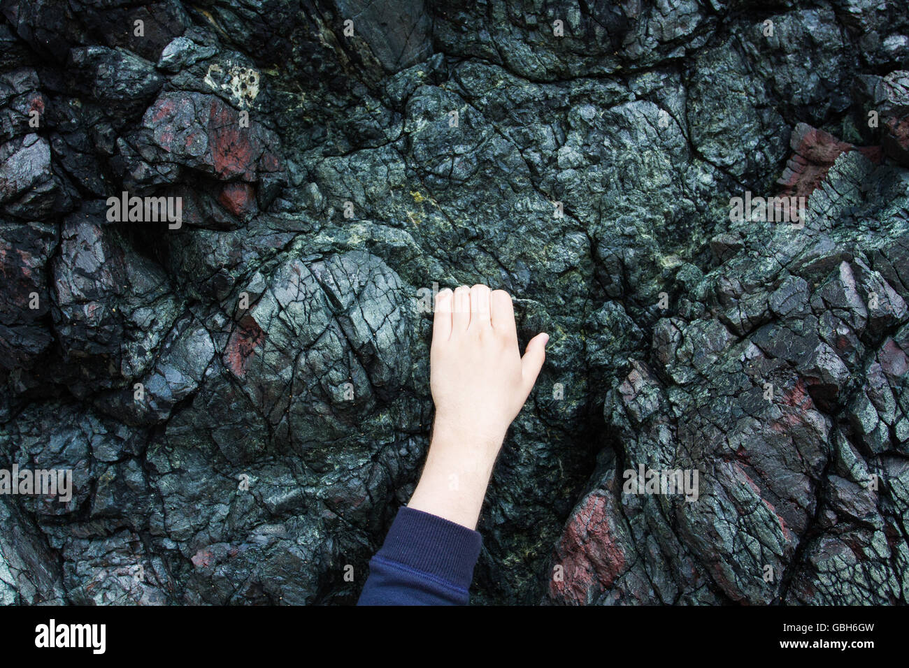 Mani aggrappati dalla punta delle dita e salendo su un aspro, roccia di granito faccia. Foto Stock