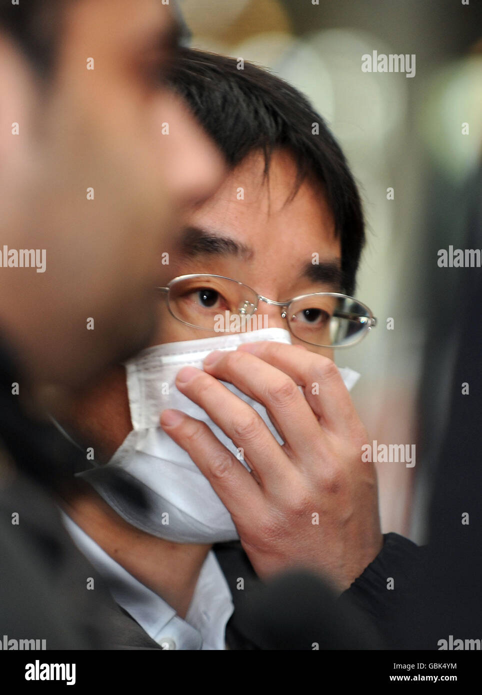 Un giornalista televisivo indossa una maschera di carta mentre intervistando gli arrivi all'aeroporto di Londra Heathow, da Città del Messico. Foto Stock