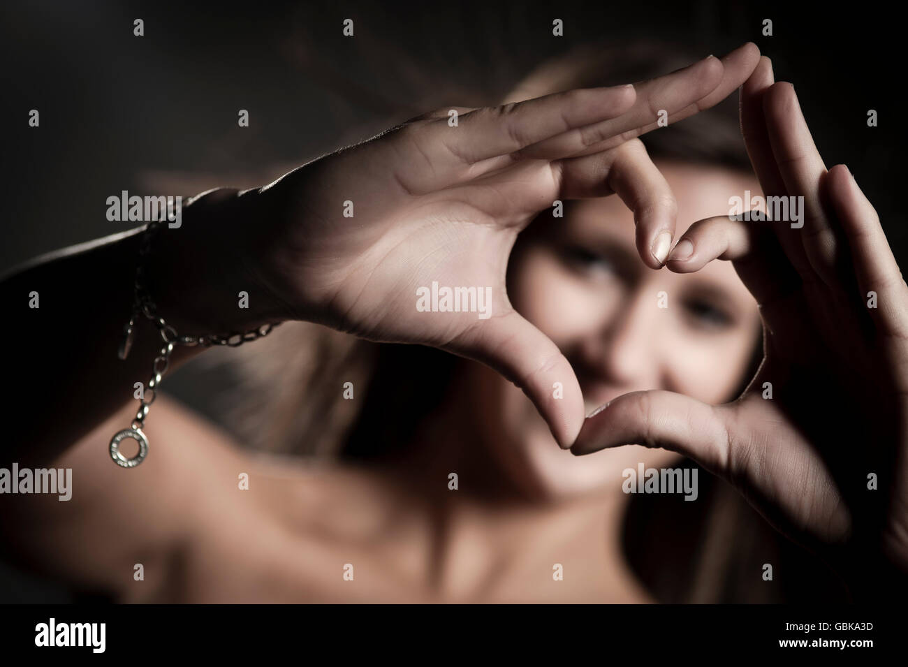 Giovane donna creando un heartshape con le dita Foto Stock