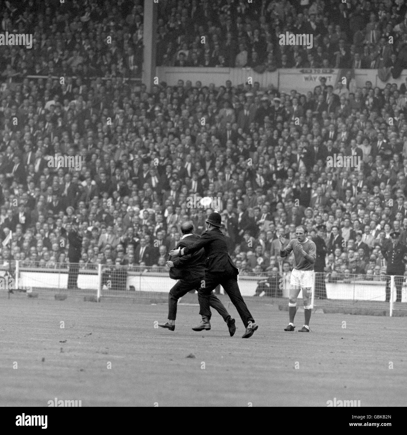 Eddie Kavanagh (l), fan di Everton, si prepara a gettare la giacca come poliziotto, allietato da Ray Wilson (r) di Everton, fa una presa per l'invasore estatico del campo, che ha fatto la sua offerta per la stella dopo l'obiettivo di equalizzazione di Everton Foto Stock