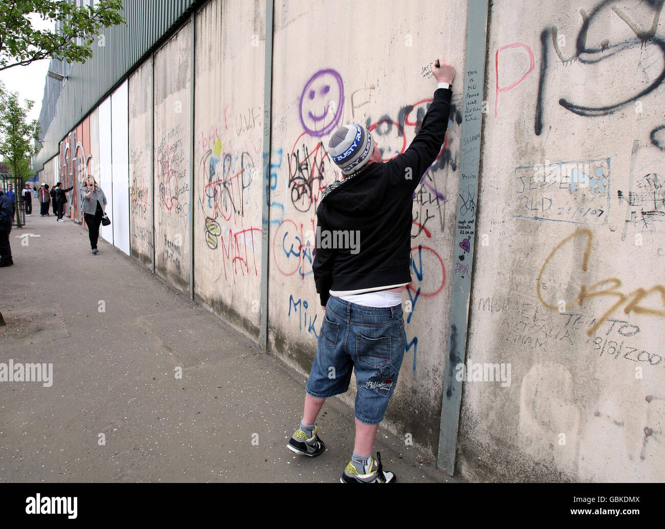 I turisti aggiungono messaggi al muro della pace di Belfast. Foto Stock