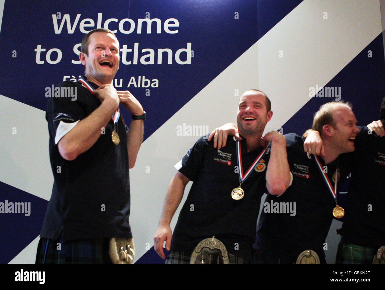 I membri della squadra di Curling Scozzese Peter Smith, Euan Byers e Ewan MacDonald ritornano con le loro Medaglie d'oro all'aeroporto di Edimburgo, Edimburgo, Scozia . Foto Stock