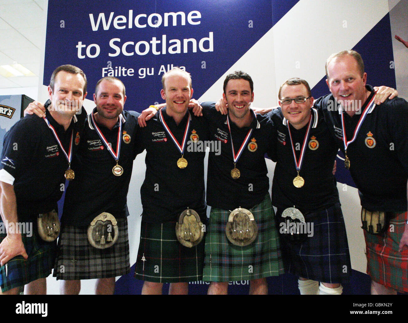 I membri del team Scottish Curling, Peter Smith, Euan Byers, Ewan MacDonald, David Murdoch, Graeme Connal e Dave Hay (da sinistra a destra), tornano all'aeroporto di Edimburgo, Scozia. Foto Stock