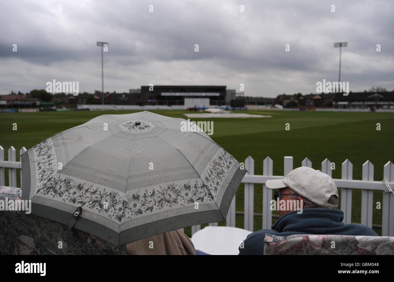 Gli spettatori si riparano sotto gli ombrelli, mentre la pioggia forza le coperture dopo solo pochi passi di gioco durante il Tour Match al County Ground, Derby. Giovedì 30 aprile 2009. Vedi la storia di PA CRICKET England Lions. Il credito fotografico dovrebbe essere: Cavo PA. Foto Stock