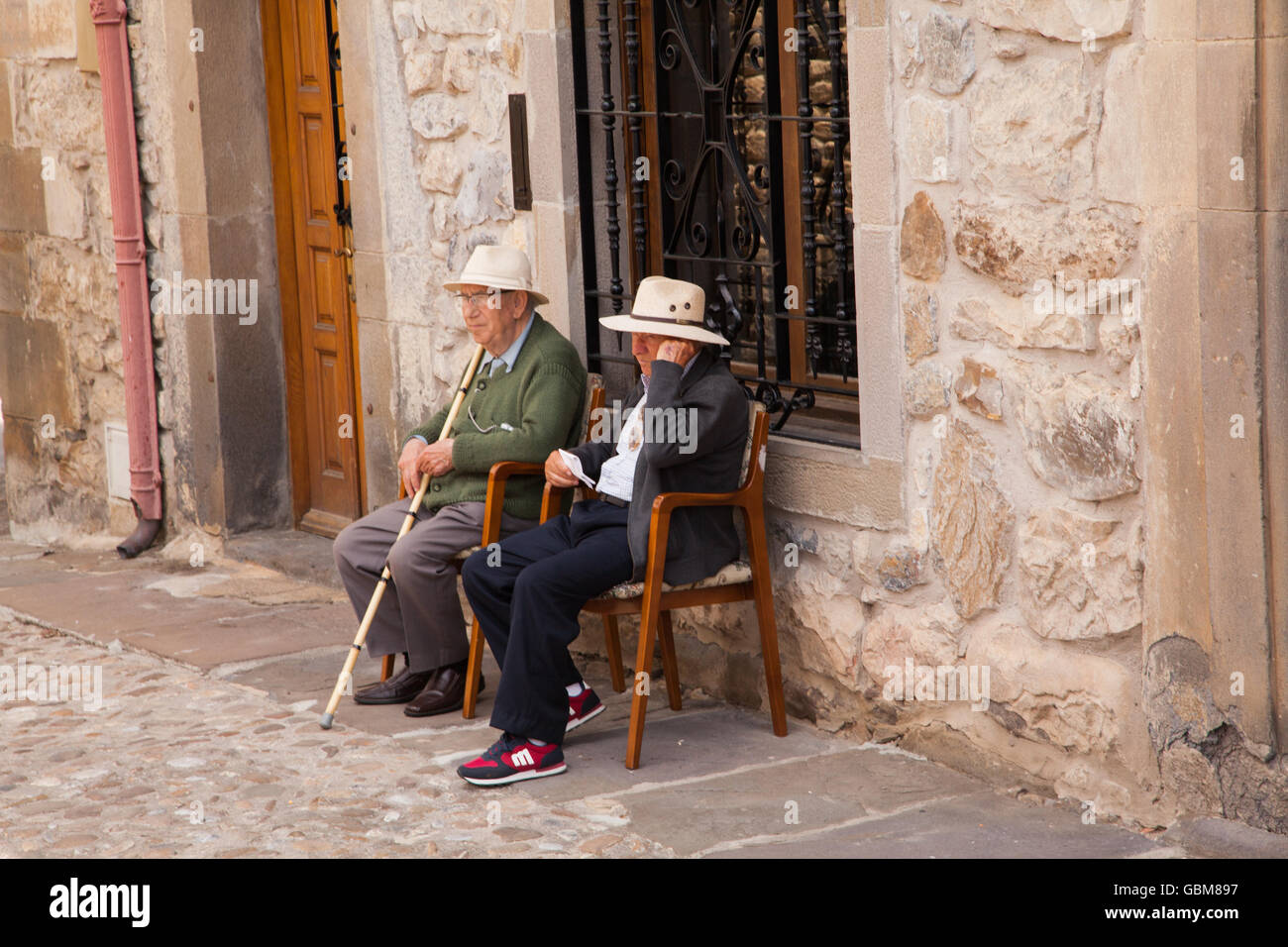 Due uomini anziani indossare cappelli seduti su sedie al di fuori di una casa a Potes Spagna settentrionale Foto Stock