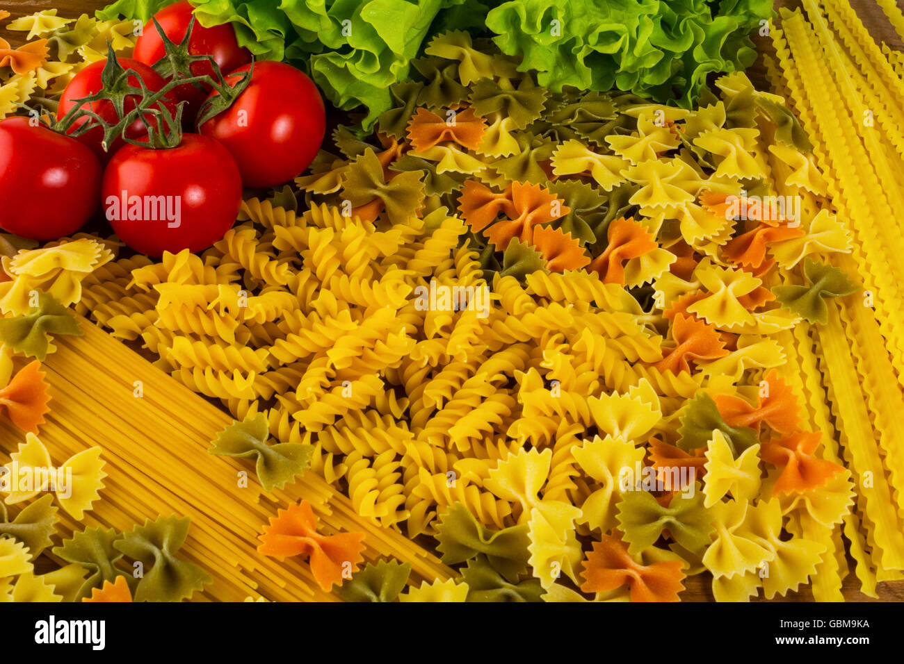 Vari tipi di pasta italiana e pomodoro ciliegino. Spaghetti. La pasta. Il cibo italiano. Tagliatelle. Foto Stock
