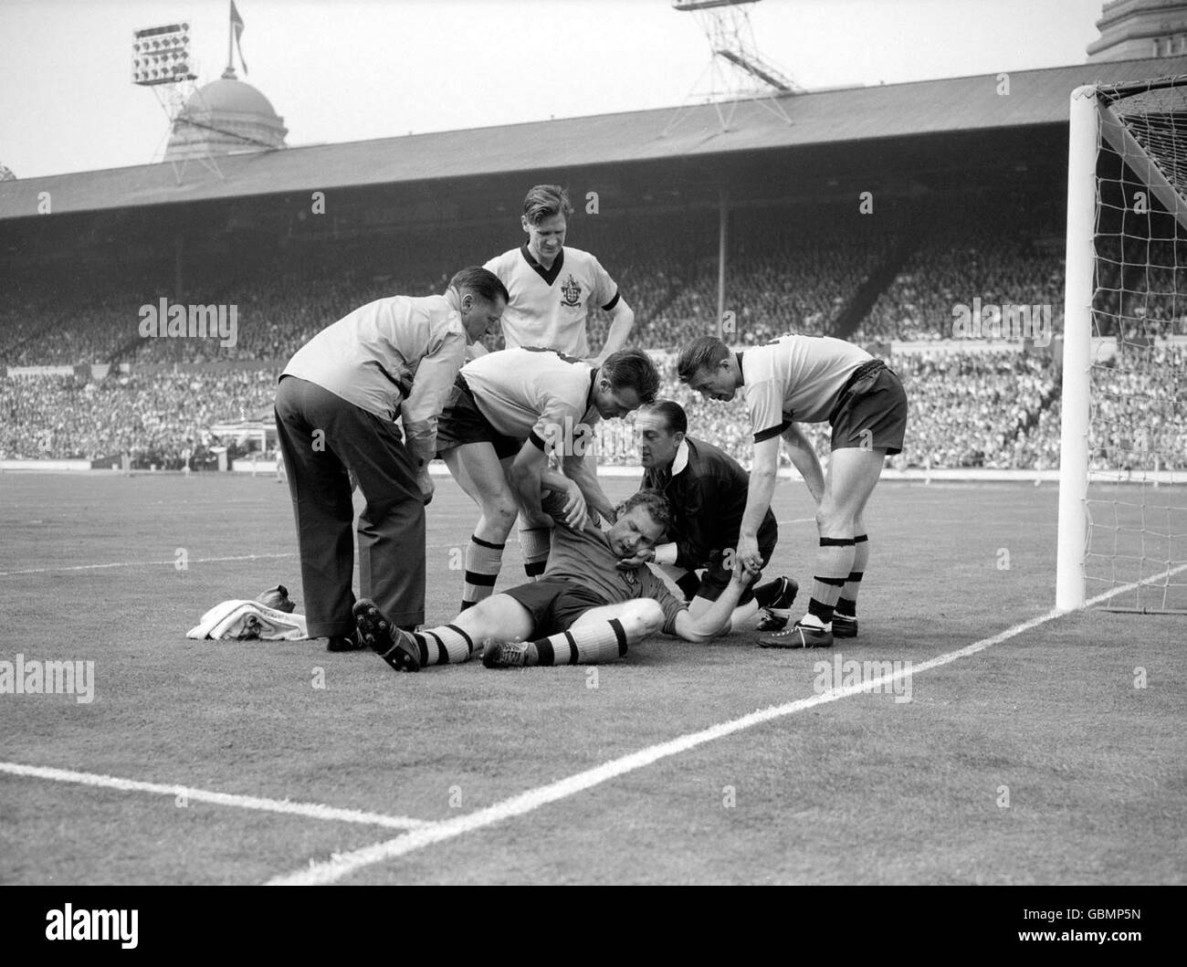 L'arbitro Kevin Howley (secondo r) sostiene il capo del portiere di Wolverhampton Wanderers Malcolm Finlayson (c) come compagni di squadra George Showell (r), Gerry Harris (secondo l) e Bill Slater (secondo l) controllano le sue condizioni Foto Stock