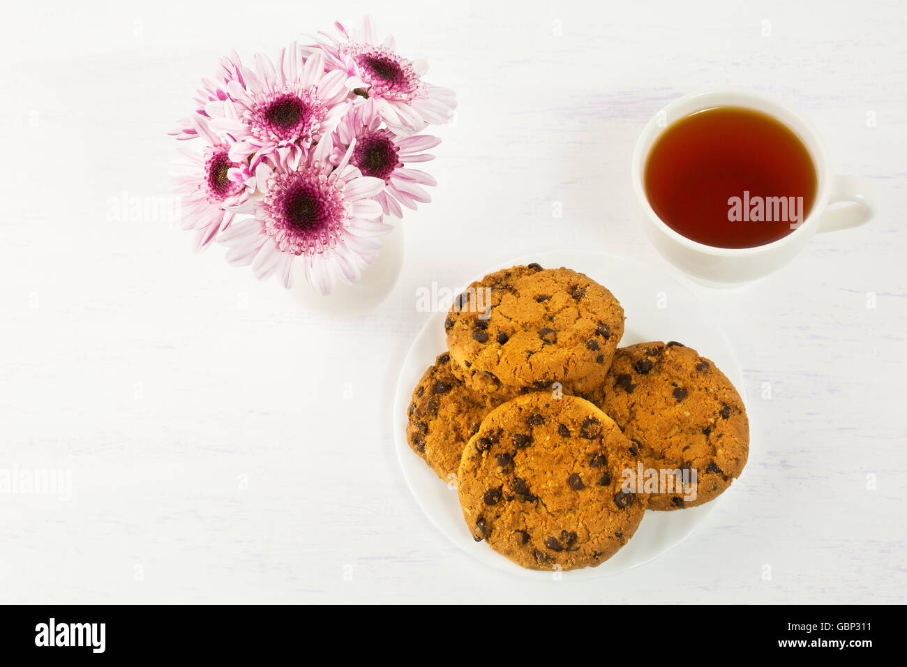 Romantico ora del tè con biscotti al cioccolato. Colazione casalinga i cookie e la tazza di tè serviti con lillà daisy Foto Stock