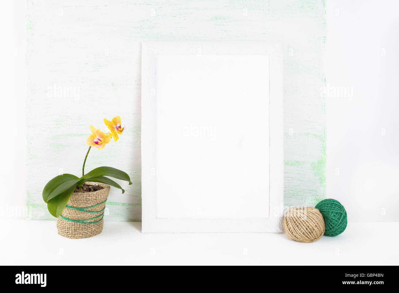 Cornice bianca mockup con orchidea gialla. Fotogramma poster mockup. Vuoto telaio bianco mockup per design presentazione. Foto Stock