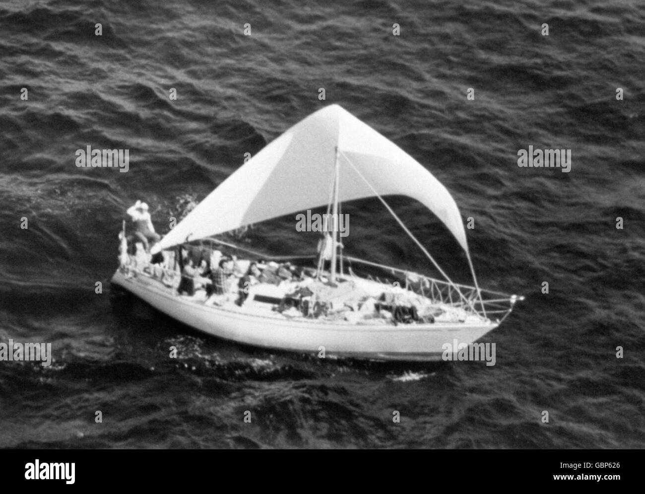 L'allegro equipaggio di uno yacht da corsa Fastnet ondeggia verso l'elicottero di controllo mentre sono avvistati sotto un banco di giuria, 150 miglia a nord ovest di St Ives, dopo feroci gales ha mietuto 15 vite. Foto Stock