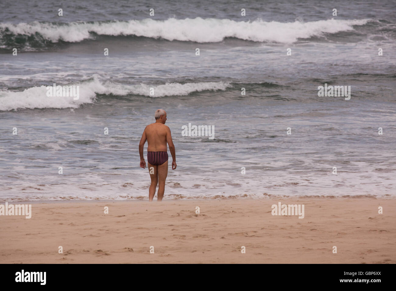 L uomo che sta per andare a nuotare in mare a Comillas Spagna settentrionale Foto Stock