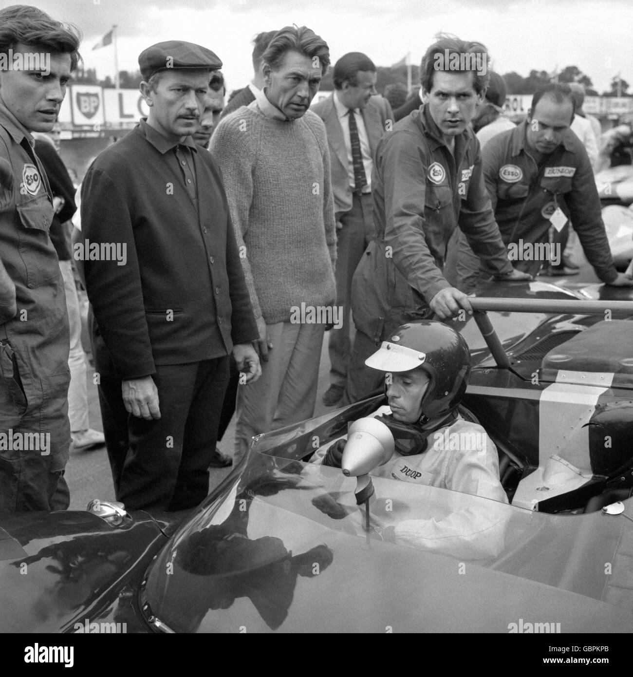 Il boss del team Lotus Colin Chapman, a sinistra con la testa piatta, ha un'espressione glum che si abbina a quella del nuovo campione del mondo del Gran Premio Jim Clark sulla griglia di partenza a Brands Hatch, Kent. Clark stava per guidare nella seconda parte della gara Guards International Trophy, ma soffriva di problemi al motore. Foto Stock