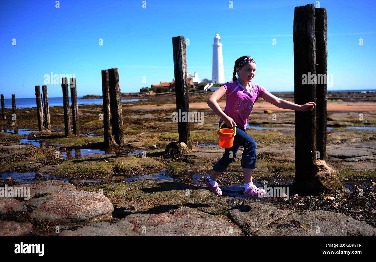 Una giovane ragazza, nome non dato, gode la mini ondata di caldo al faro di St Mary, Whitley Bay Northumberland oggi come il paese si crogiola al sole. Foto Stock