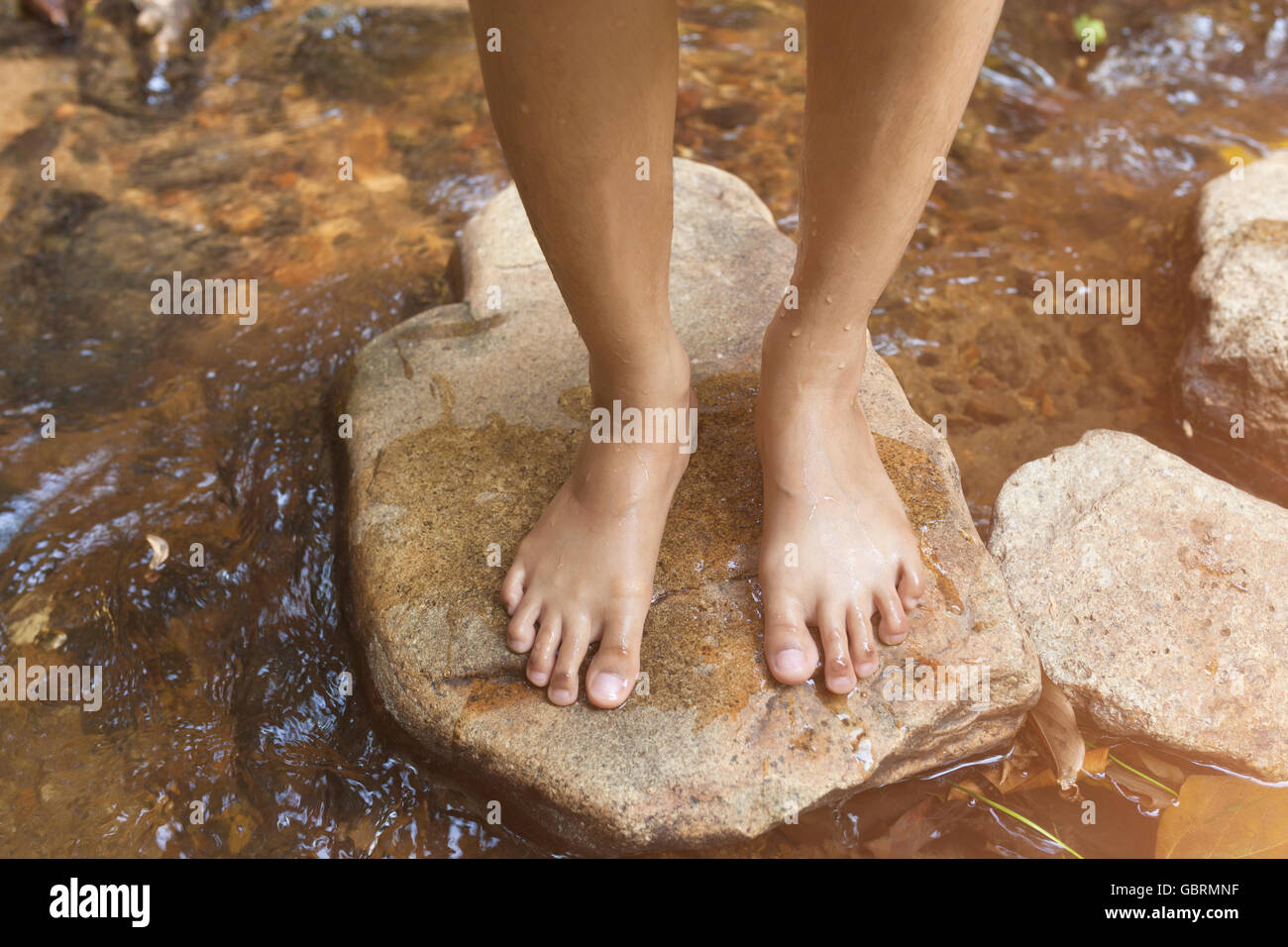 Piedi di donna che cammina sulla pietra vicino al fiume. Foto Stock