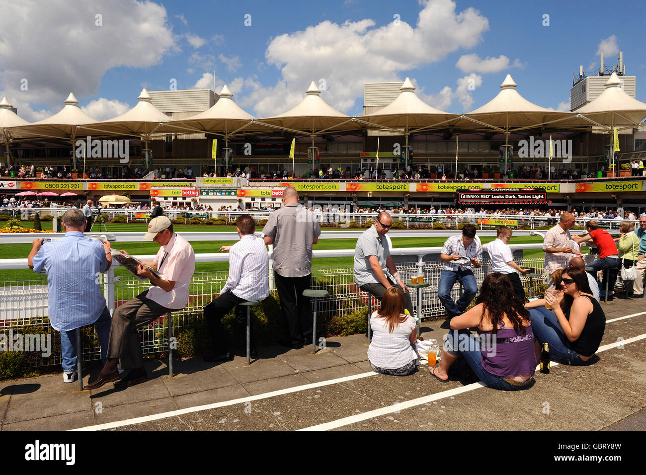 Corse di cavalli - Totepool Irish Day - Sandown Park. I Racegoers si siedono accanto al Parade Ring durante l'Irish Day al Sandown Park. Foto Stock