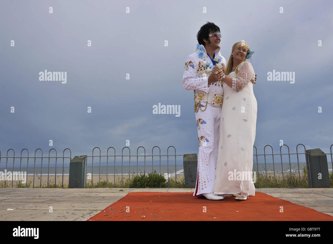 Steve Caprice, un importante artista professionista elvis tributo, e un ministro completamente ordinato, con sua moglie Barbara dopo il loro matrimonio di cerimonia civile a Porthcawl, Galles. La cerimonia è stata una fedele ricreazione della scena di nozze dal film Blue Hawaii di Elvis. Foto Stock