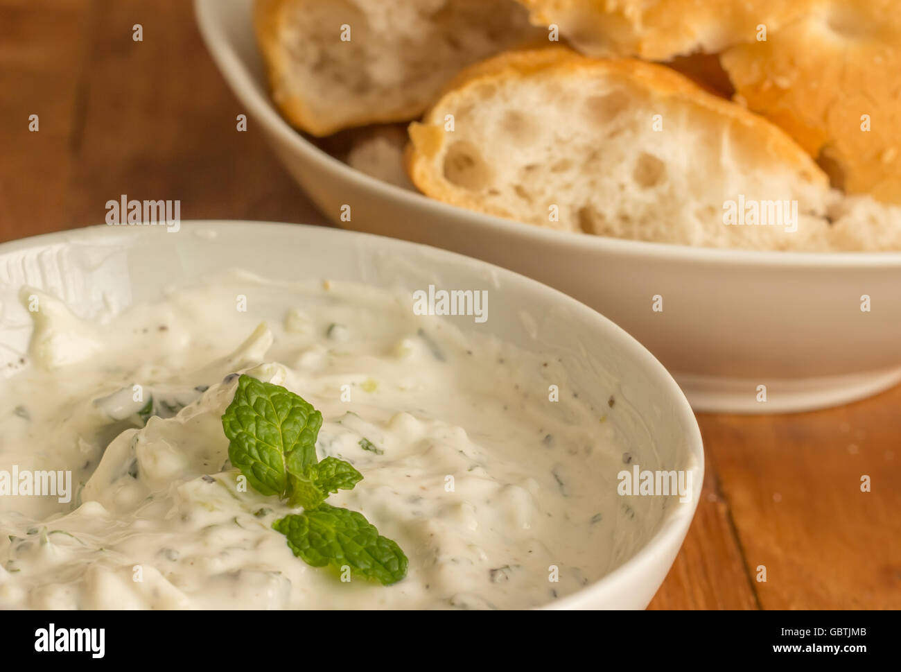 Yogurt, menta e salsa di limone con pane bianco su un tavolo di legno Foto Stock