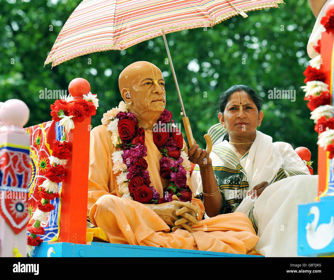 Un devoto di Hare Krishna tiene il sole da una statua di legno su un gigantesco santuario ornamentale su ruote, uno dei tre che è stato tirato a mano da Hyde Park a Trafalgar Square per celebrare il 'Ratha-yatra' Festival. Foto Stock