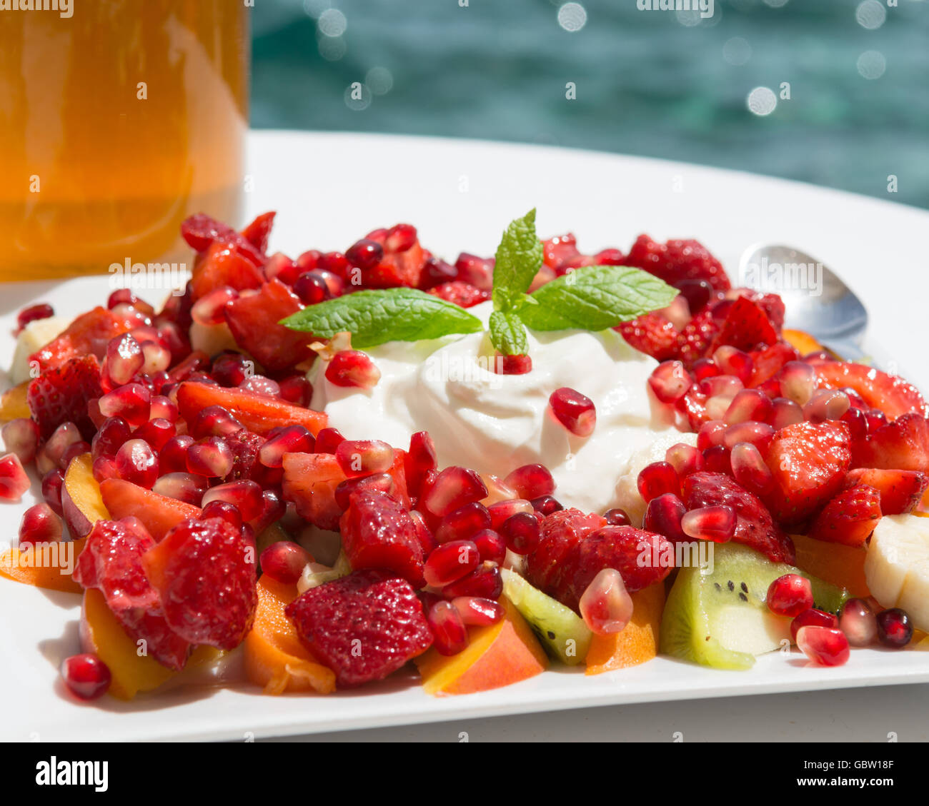 Holiday Colazione - yogurt greco, greco il miele, melograni, kiwi, pesche, fragole, prima colazione che si affaccia sul mare - Grecia Foto Stock