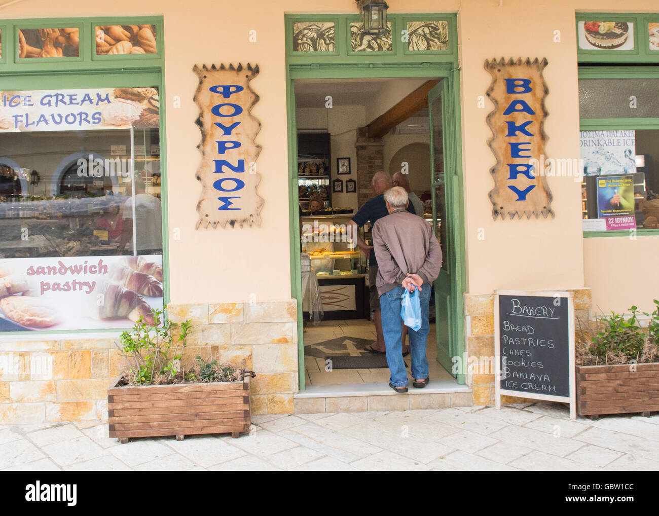 Gli uomini in coda per mattina il pane e pasticceria presso la panetteria - Lakka, Paxos Grecia, Europa Foto Stock