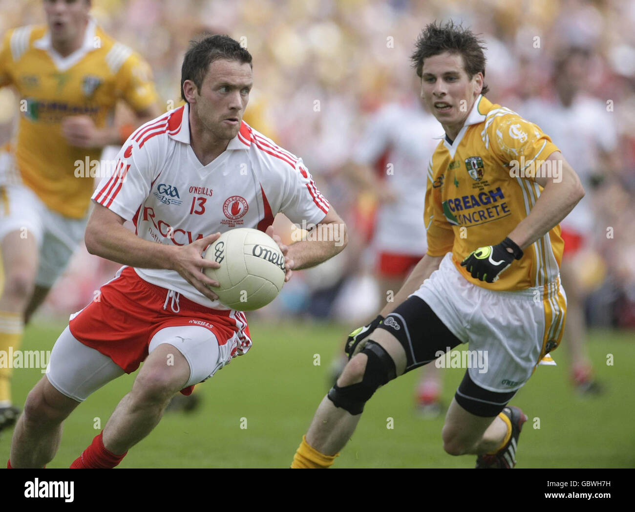 Martin Penrose di Tyrone (a sinistra) è inseguito da Kevin o'Boyle di Antrim durante la finale di football del campionato Ulster al St Tiernachs Park di Clones, County Monaghan, Irlanda. Foto Stock