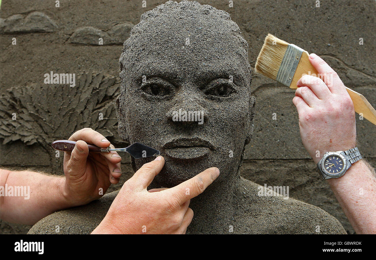 L'artista Daniel Doyle e il nipote Nathaniel hanno messo le finiture in una scultura di sabbia a grandezza naturale utilizzando due tonalità di sabbia. La scultura illustra l'impatto umano del cambiamento climatico durante il lancio di Oxfam Irlanda delle vite di Climate Change Destroy - Let Face IT a Dublino. Foto Stock