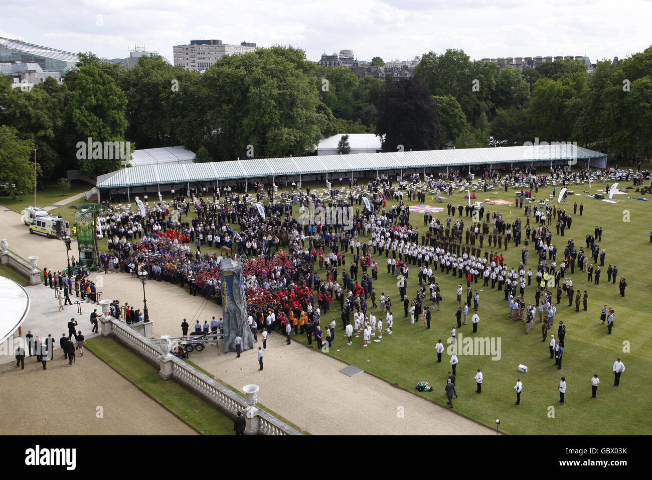 Il principe Carlo e la duchessa di Cornovaglia (a sinistra in cima al gradino), arrivano per una festa reale dei Giardini a Buckingham Palace a Londra dove si incontrarono con giovani e volontari adulti per LANCIARVI Londra (uniforme delle organizzazioni giovanili). Foto Stock