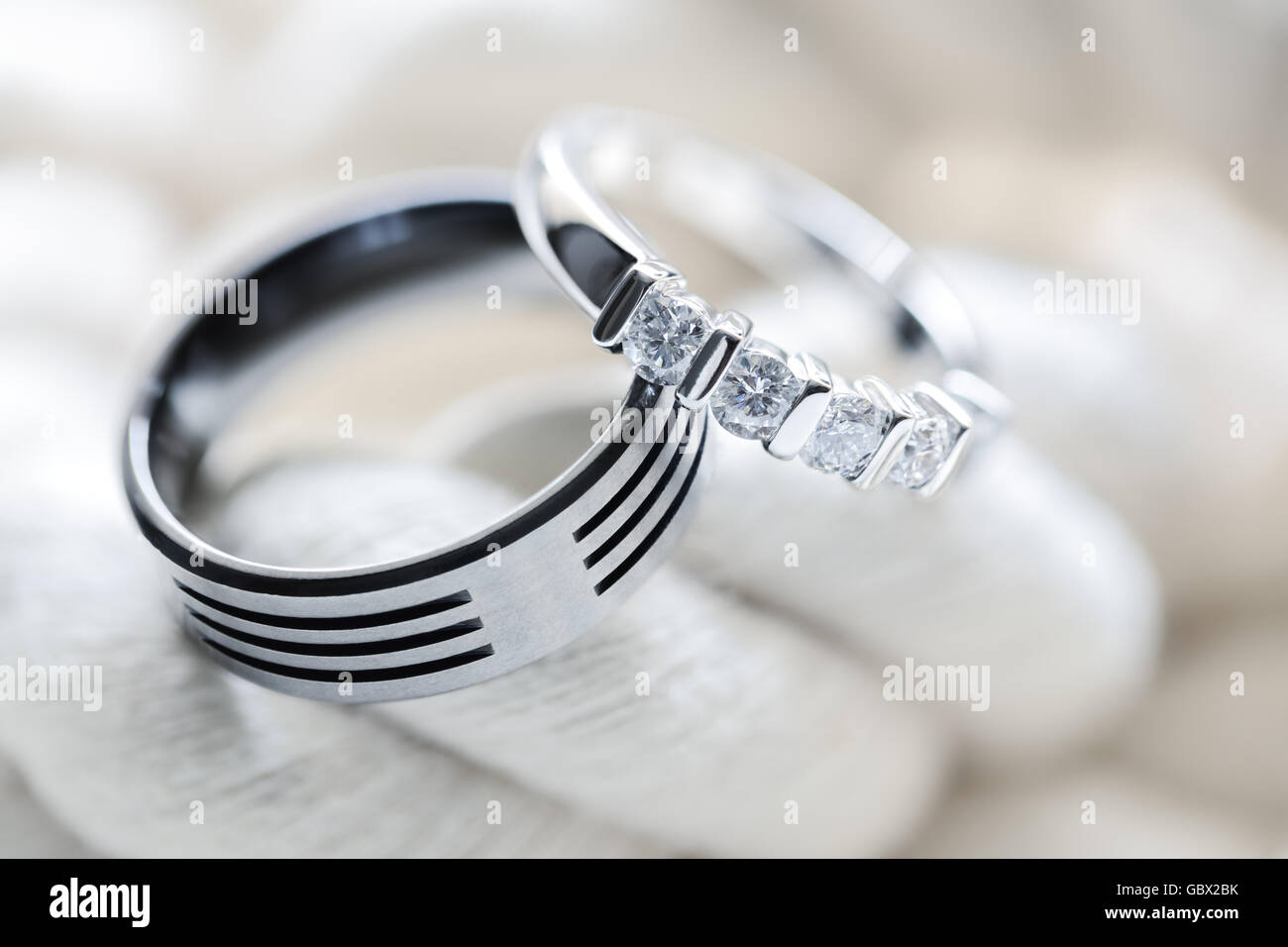 Due argento platino e diamante di Titanio anelli di nozze su bianco sullo sfondo di corda Foto Stock