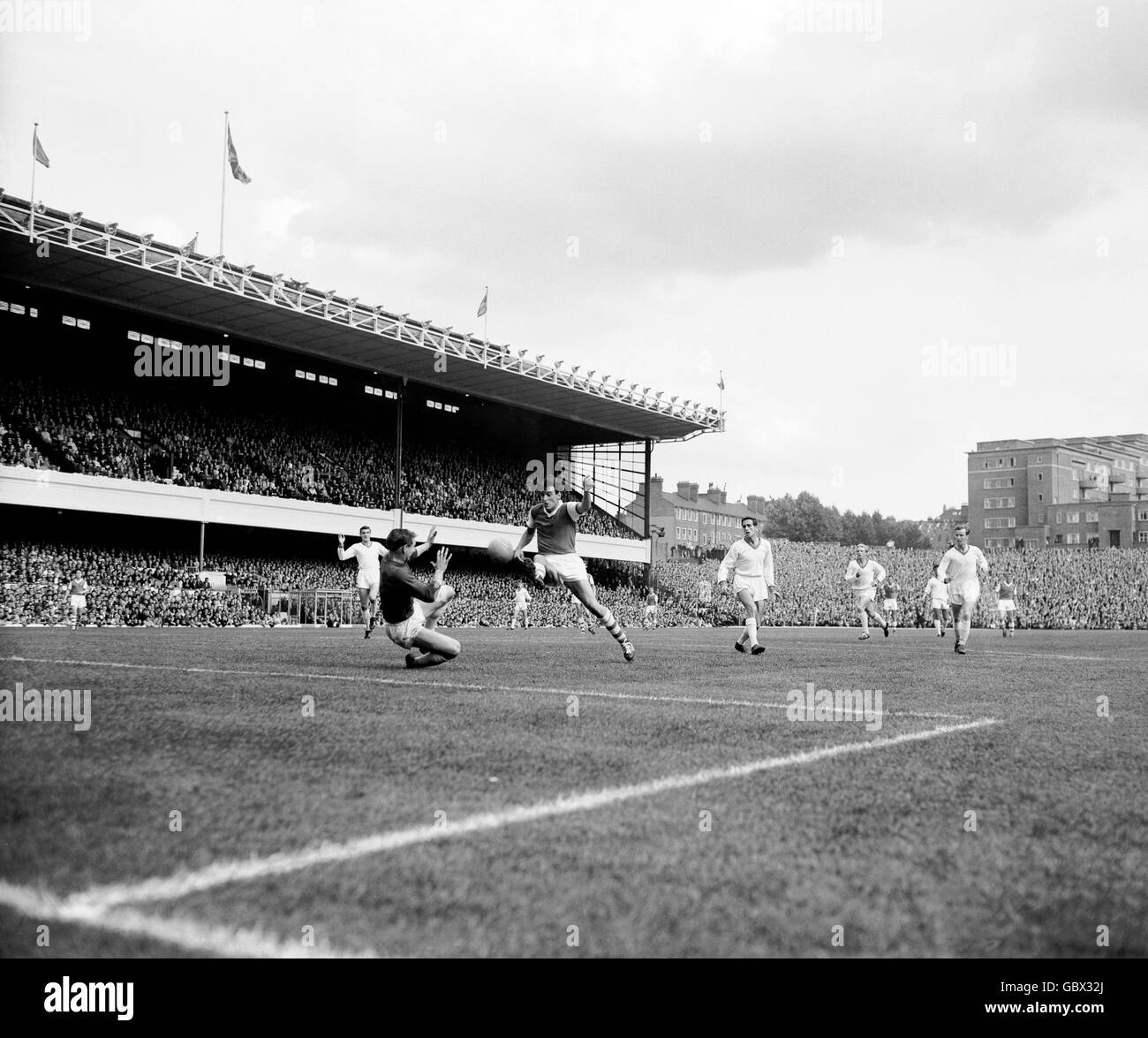 Alan Skirton di Arsenal (terzo l) spara un colpo dopo il portiere del Manchester United David Gaskell (secondo l), guardato da Bill Foulkes di United (l), Shay Brennan (terzo r), Denis Law (secondo r) e Noby Lawton (r) Foto Stock