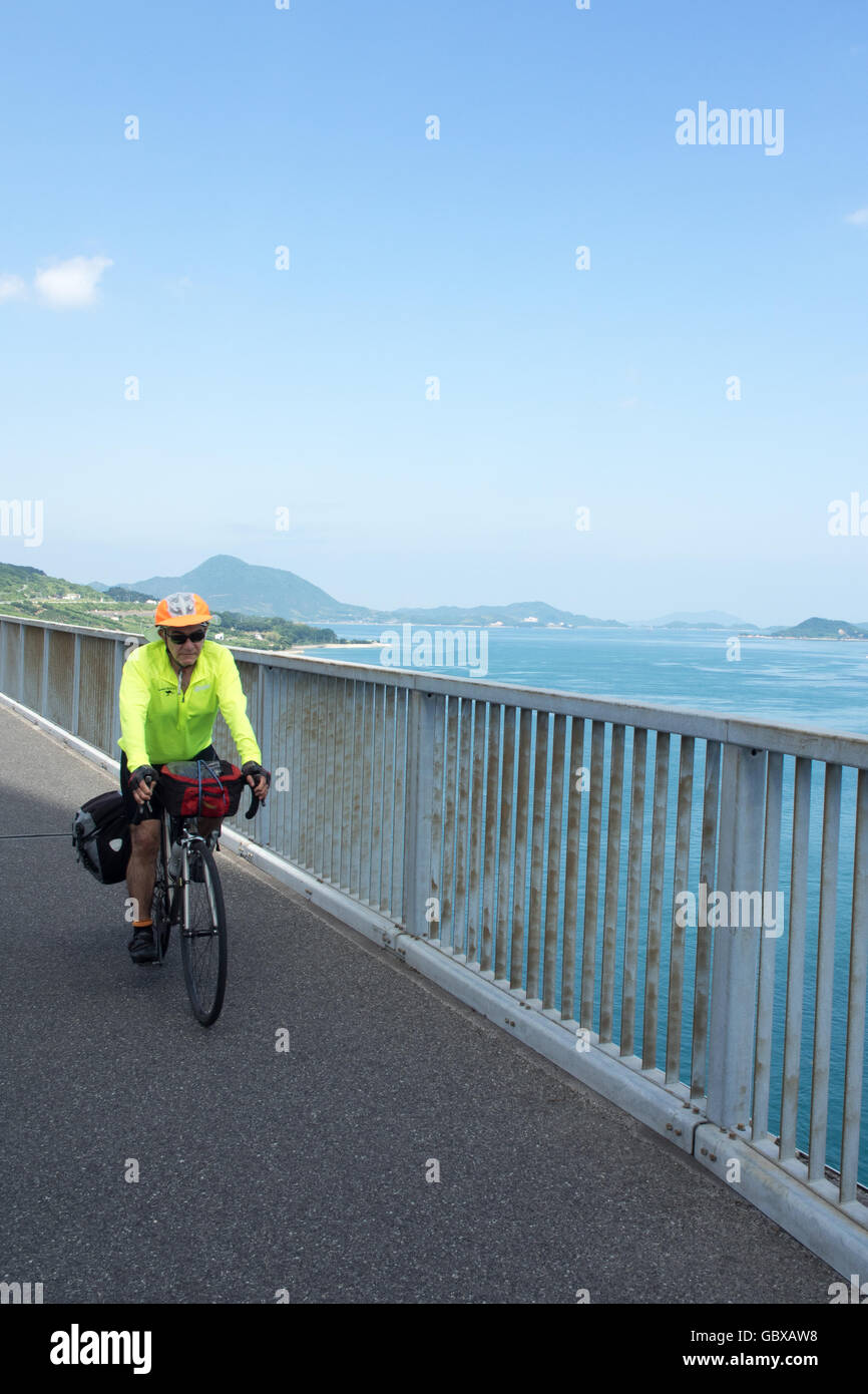 Una touring ciclista pedalare attraverso la Tatara ponte di collegamento tra le isole di Omishima e Ikuchi in Seto Inland Sea. Foto Stock