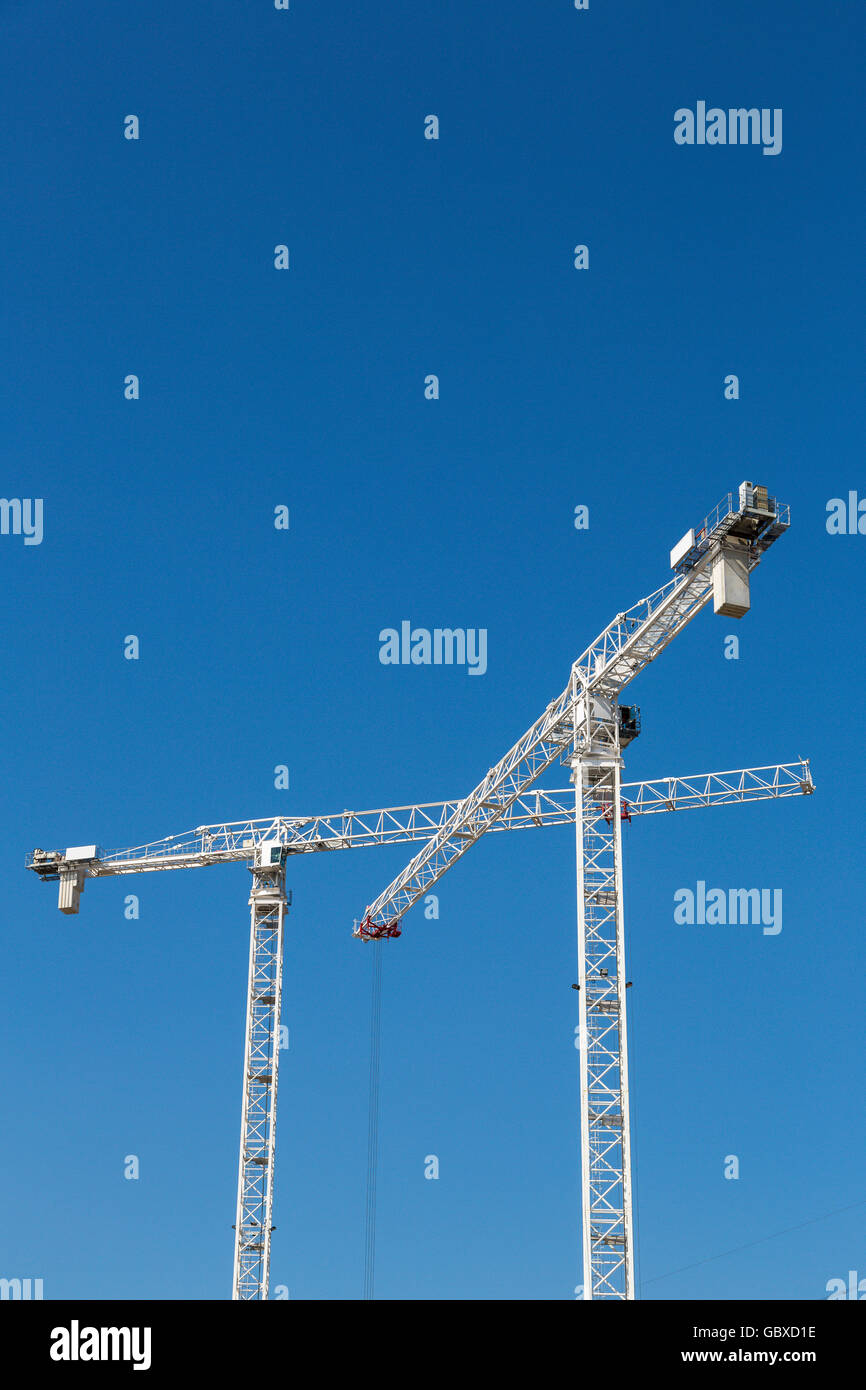 Due gru a torre di lavoro a Londra contro il cielo blu Foto Stock