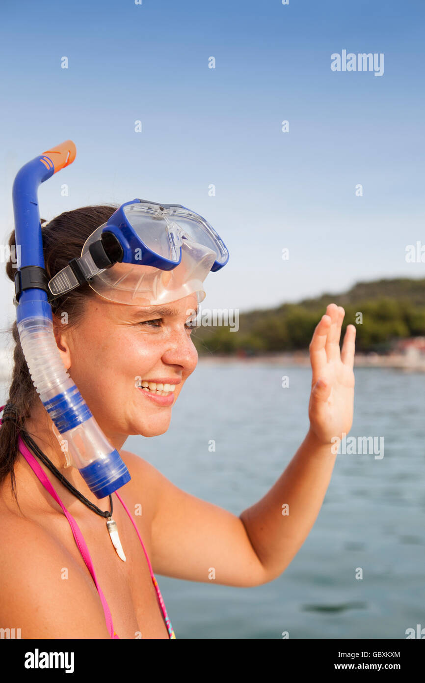 Bella ragazza al mare indossando una maschera subacquea e salutando Foto Stock
