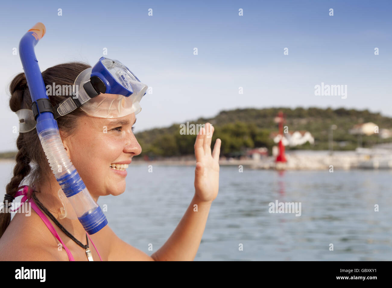 Bella ragazza al mare indossando una maschera subacquea e salutando Foto Stock