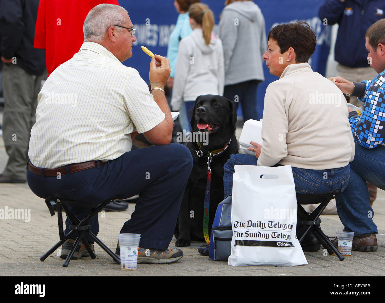 Un cane guarda le fiches mangiare del suo proprietario a Cowes Yacht Haven durante la settimana di Cowes, la regata di vela famosa in tutto il mondo che si tiene ogni anno sul Solent, dove gli incassi sono giù. Oggi gli organizzatori hanno smesso di addebitare agli spettatori l'ingresso alle feste serali a causa della mancanza di commercio. PREMERE ASSOCIAZIONE foto. Data immagine: Martedì 4 agosto 2009. La recessione è stata accusato di aver registrato un calo di circa il 15% rispetto agli anni precedenti. Circa 900 yacht si contenderanno negli otto giorni di gara durante il 183° anno dell'evento. Il credito fotografico dovrebbe essere: Chris Ion/PA Wire Foto Stock