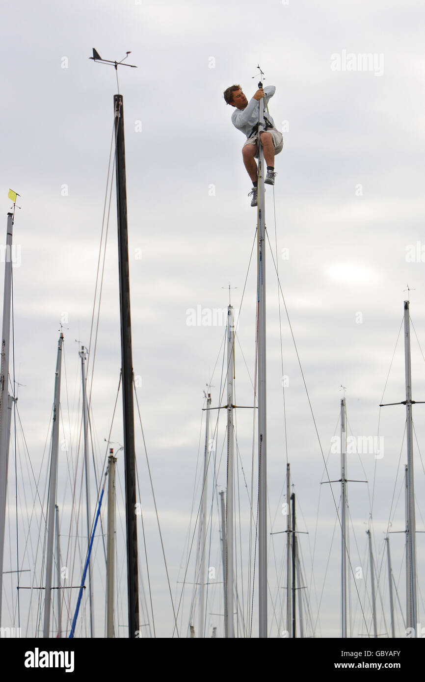 Un concorrente sostituisce il puntatore del tempo in testa al suo albero prima di una giornata di corse durante la settimana dei Cowes sull'isola di Wight. Foto Stock