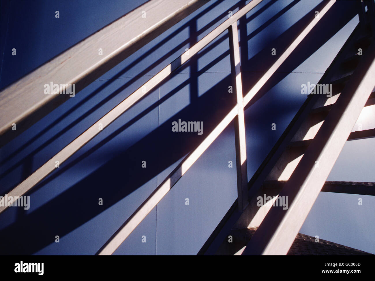 Scala industriale getta ombre sulla grande torre d'acqua serbatoio Foto Stock