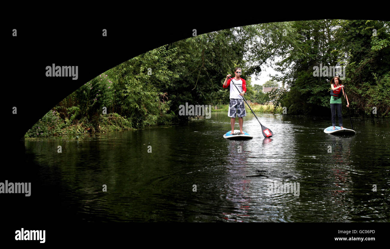 L'istruttore di paddle board Rowland Gurner e Nicola Stroud di Fen Paddle si avvicinano a un ponte mentre prendono le loro paddle board lungo la River Cam di Cambridge, Cambridgeshire. Foto Stock