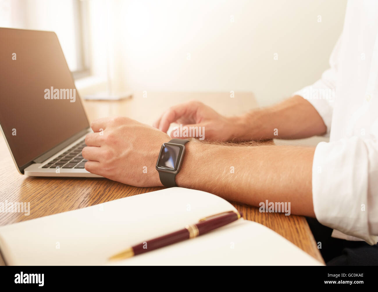 Chiudere l immagine dell uomo d affari lavorando sul computer portatile. Uomo con un smartwatch utilizzando computer portatile mentre è seduto alla sua scrivania. Foto Stock