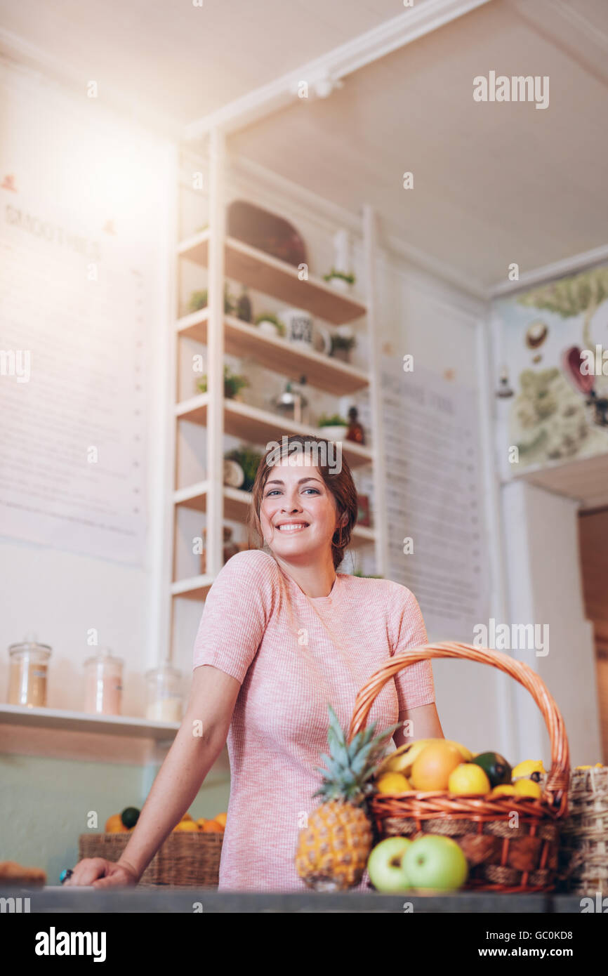Sorridente juice bar proprietario in piedi dietro il bancone e guardando la fotocamera. Giovani caucasici donna che lavorano nel bar dei succhi. Foto Stock