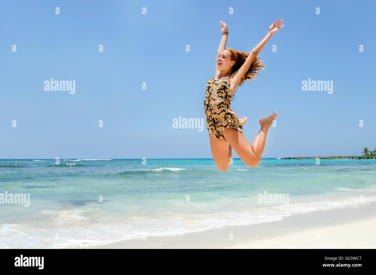 Redhead girl jumping in spiaggia Foto Stock