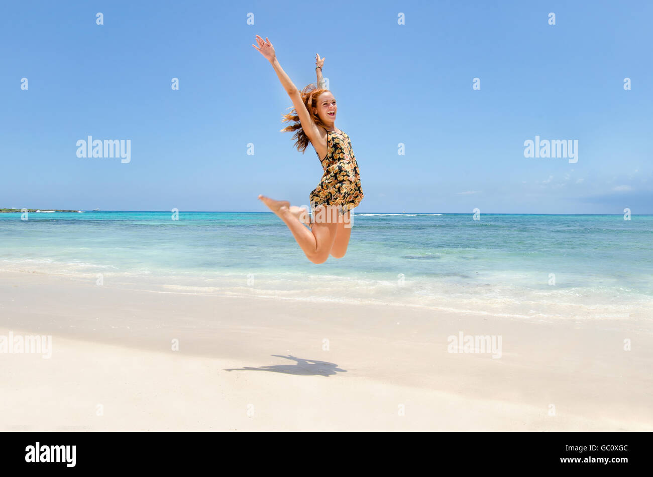 Bella redhead jumping in spiaggia Foto Stock